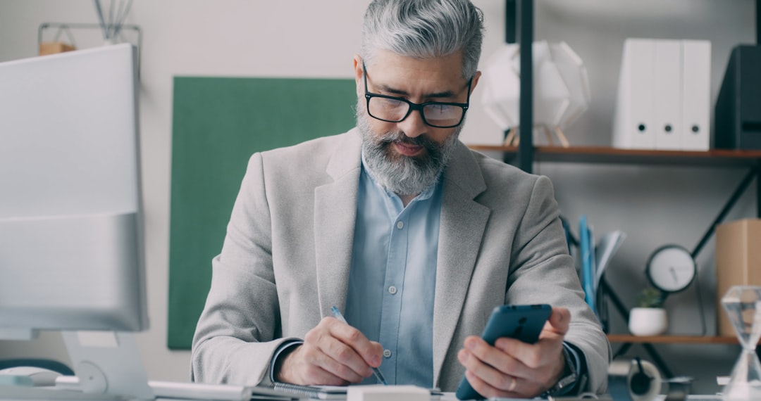 a-man-sitting-at-a-desk-using-a-cell-phone-wilbyugreea